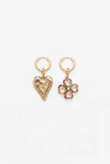 Aros colgantes dorados con argolla pequeña y dijes intercambiables: uno con forma de corazón texturizado y otro con diseño de trébol de cuatro hojas con incrustaciones de resina rosada.