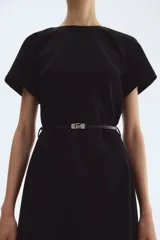 Vestido corto negro, de corte entallado, con cuello redondo y mangas cortas raglán. Incluye un cinturón fino con hebilla metálica decorativa.