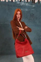 Cartera tipo bandolera de gran tamaño, confeccionada en cuero sintético con acabado desgastado. Cuenta con una asa corta fija, una correa larga regulable y extraíble, y una placa metálica con la marca en la parte frontal.