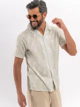 Camisa de manga corta de algodón en color beige, con cuello camisero y cierre frontal de botones, con diseño estampado sutil.