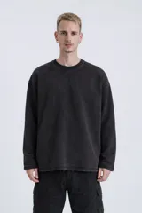 Buzo de cuello redondo con calce oversize y hombros caídos. Confeccionado en algodón gamuzado pesado con un proceso de lavado efecto nevado que genera un tono irregular. Presenta costuras expuestas a contratono y detalles de roturas en el cuello, puños y ruedo, logrando una estética desgastada.