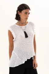 Blusa de textura rugosa en color blanco, sin mangas, con detalle de volados en los hombros y corte asimétrico en el ruedo.