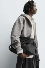 Sudadera de corte relajado confeccionada en tejido de algodón con interior afelpado. Presenta cierre frontal de cremallera, capucha con cuello subido, manga larga y acabados en rib.