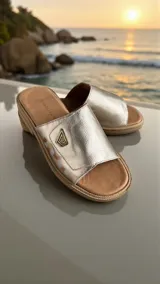 Sandalias planas de cuero color dorado pálido con detalle de arte pintado a mano en el lateral, logo metálico de la marca y base ergonómica.