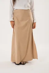 Falda larga color beige confeccionada en tela suave con acabado tipo piel de durazno y cierre invisible lateral.