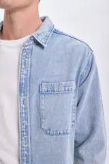 Sobrecamisa de jean celeste con cuello clásico, cierre frontal con botones metálicos, dos bolsillos de parche en el pecho y mangas largas con puños abotonados.