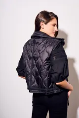 Chaleco negro con cierre frontal y cuello alto, de corte al cuerpo y diseño acolchado. Reversible, con interior a cuadros.