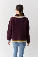 Buzo de lana tipo polo con cuello y cartera de botones en colores contrastantes. Presenta mangas con textura de ochos y puños y ruedo con terminaciones en franjas de colores.