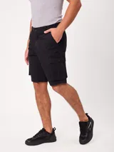 Bermuda cargo de gabardina color beige, con bolsillos laterales con fuelle en las piernas, bolsillos delanteros tipo ojal y traseros. Cuenta con presillas para cinto y cierre frontal con botón y cierre.