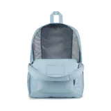 Mochila JanSport celeste con logo rectangular en azul marino y rojo. Tiene un compartimento principal grande, un bolsillo lateral para botella de agua, un bolsillo frontal con cremallera, tirantes acolchados y panel trasero acolchado.