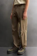 Pantalón técnico de corte regular fit en color marrón, confeccionado en tejido elástico y compacto. Cuenta con cintura ajustable con cordón interior, bolsillos frontales, bolsillo trasero con cierre oculto y bolsillo lateral con cierre en la pernera. El bajo es ajustable mediante botones a presión.