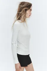 Camiseta de manga larga color gris melange, con cuello redondo y bajo recto. Presenta un detalle de tejido efecto doble a contraste en el cuello, puños y dobladillo inferior en color blanco.