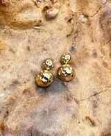 Par de aros dorados con diseño de doble esfera texturizada.