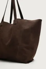 Bolso tipo shopper de gran tamaño confeccionado en piel con acabado de serraje. Presenta un diseño minimalista con costuras visibles, compartimento principal amplio y dos asas de hombro integradas.