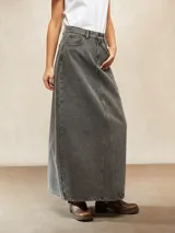 Falda larga de jean color gris oscuro, con corte en A y costuras verticales decorativas en el frente. Tiene bolsillos laterales y cierre con botón y cremallera.