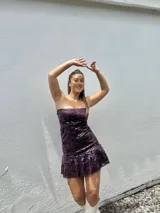 Vestido corto con estampado de rayas horizontales en tonos grises y negros. Diseño con escote halter que se ata al cuello, abertura central en el busto y falda corta con volado.