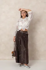 Pollera larga de pana color chocolate, con diseño de tablas frontales y bordados florales en toda la superficie. Cuenta con cintura con pasacintos.