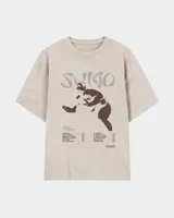 Remera oversize color beige con cuello redondo y diseño gráfico impreso en el frente, que incluye la silueta de un luchador de sumo y tipografía alusiva.