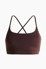 Top deportivo SculptMove color marrón, con escote redondo, breteles finos cruzados en la espalda y bajo elástico. Cuenta con copas forradas con relleno extraíble.