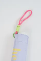 Paraguas plegable de color beige con la palabra 'hello.' estampada en color verde. Incluye una correa de muñeca de color amarillo con detalles en fucsia.