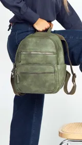 Mochila color marrón claro de símil cuero con bolsillos frontales con cierre. Tiene asa de mano rígida y correas regulables.