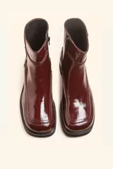 Bota corta de cuero vacuno con acabado charol brillante, diseño de punta cuadrada y suela de caucho con pequeña plataforma.