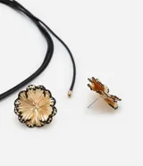 Conjunto de collar y aros dorados con forma de flor. Los aros son tipo botón y el collar es de cordón negro.