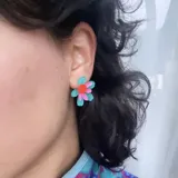 Aros tipo botón con forma de flor de pétalos turquesa y centro rosa y naranja.