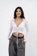 Crop top negro de manga larga con cuello polo, escote en V y detalle de frunce central ajustable con cordones.