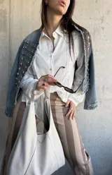 Camisa blanca de manga larga con detalles de encaje y calados verticales en el frente y las mangas.