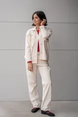 Pantalón de jean color crudo, de corte recto, con detalle de piedras de colores en los bolsillos delanteros y traseros.