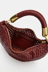 Bolso de hombro bordó con diseño trenzado y forma curva tipo hobo. Cuenta con un asa corta estructurada con detalles metálicos dorados en los extremos.