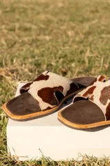 Sandalias bajas de cuero con estampado animal print de vaca en marrón y blanco.