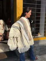 Poncho de lana merino tejido en telar de peine, color marfil con diseño a cuadros en tonos azul marino y rojo, terminado con flecos en el ruedo.