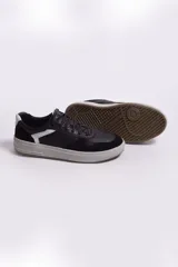Zapatillas urbanas de cuero negro con detalles en cuero gamuzado y cuero perforado. Presentan una banda lateral blanca y suela de goma color tiza.