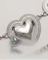 Cinto de metal plateado con diseño de dijes en forma de corazón repujado unidos por cadenas y tira colgante.