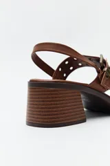 Sandalias negras de cuero sintético con doble tira y hebillas metálicas plateadas. Taco cuadrado bajo y tira trasera con hebilla.