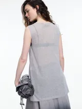 Musculosa de tejido fino y translúcido con sutil brillo metálico, de corte relajado, sin mangas y largo por debajo de la cadera con aberturas laterales.