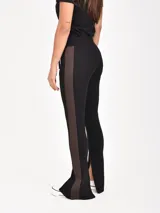 Pantalón negro con franja lateral marrón, cintura elástica con cordón ajustable, bolsillos laterales con cierre y cierres en los tobillos.