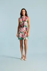 Vestido corto sin mangas con cuello alto y lazo colgante, de diseño recto y estampado floral multicolor sobre base rosada.