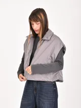 Chaleco acolchado color mostaza, con cuello camisero, cierre frontal con cremallera y diseño holgado sin mangas.