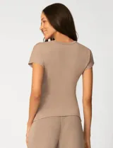 Remera de manga corta color beige, confeccionada en mezcla de modal, con cuello redondo y detalle de lazo lateral que genera un drapeado natural en la cintura.