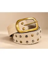 Cinto de cuero recubierto con pelo color beige, adornado con tachas metálicas alternadas en tonos dorados y plateados, hebilla rectangular grande de bronce.