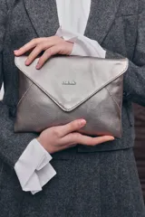 Bolso tipo sobre color plateado metalizado con diseño en forma de sobre y cierre de solapa magnética.