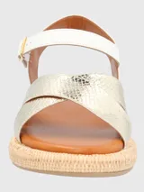 Sandalia de plataforma con base tejida tipo esparto. Presenta tiras delanteras entrecruzadas en material metalizado con textura de piel de serpiente y tira trasera blanca con ajuste de hebilla metálica.