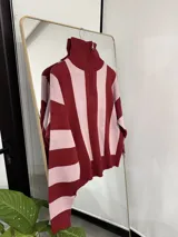 Sweater de punto con diseño a rayas verticales en color bordó y rosado, cuello alto con cierre frontal y mangas largas.
