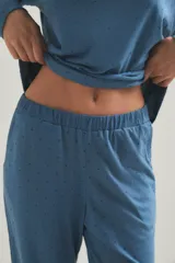 Pijama de dos piezas compuesto por una remera de manga larga con cuello redondo y un pantalón de corte recto y holgado. Ambas prendas presentan un estampado de pequeños puntos oscuros sobre una base de color azul.