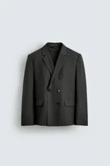 Blazer de corte regular confeccionada en tejido con lana, con diseño de botonadura cruzada. Presenta cuello con solapas de pico, manga larga con puños abotonados, bolsillos de solapa en la cadera y abertura central en la espalda.