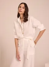 Camisa blanca de lino, de corte clásico, con cuello camisero y mangas largas con puños abotonados.
