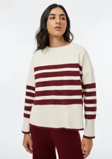 Buzo de tejido de punto con diseño de rayas horizontales en color bordeaux y crema, cuello redondo y mangas largas con puños acanalados.